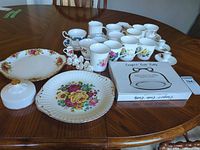 Group shot of all china pieces, candle holders and boxed caddy on table
