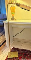 Full view of brass floor lamp showing base, standard, arm and shade