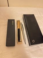 Three pen boxes and two visible pens laid out