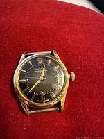Front view of Rolex Oyster Perpetual case showing black dial and gold-tone bezel