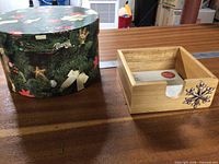 Round Christmas patterned box beside wooden napkin holder with snowflake and napkins