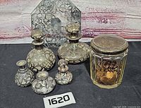 Group view of two large and three small silver overlay perfume bottles, faceted jar with metal lid, hexagonal mirror tray