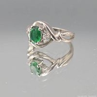 angled view of sterling silver ring highlighting green oval stone and accent stones