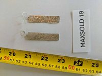 Both earrings beside tape measure showing approx 2.25 inch length
