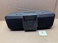 Front view of Sony CFD-703 boombox showing speakers, control panel, cassette deck and note card