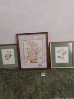 Three framed floral art prints on carpet