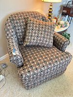 Front view of upholstered swivel armchair with pillow