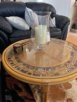 Round bamboo coffee table with glass vase, candle and coaster holder displayed on top