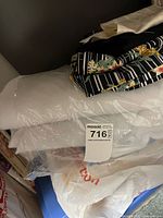 Stack of fabrics and plastic-wrapped batting on shelf