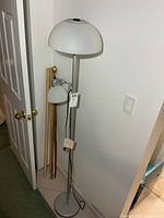Full view of lamp beside wall showing height, pole, base, shades