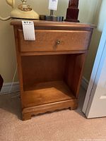 Front view of night table showing drawer, open shelf and scalloped base