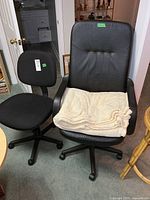 Large and small black office chairs with cream blanket draped over seat