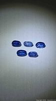 Five oval blue kyanite gemstones on neutral background