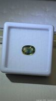 Oval tri-colored sapphire in display box, top view