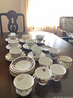 Full group of assorted teacups and saucers on table