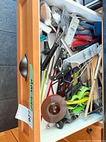 Drawer view showing mixed utensils including knives, spatulas, wooden spoons, tongs, ladle