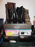 Photo of five pairs of women’s footwear placed on top of four shoeboxes showing brand labels for Dansko, Harley Davidson, and Chinese Laundry.