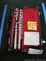 Image showing the complete disassembled chrome flute inside the original hard case lined in red velvet, including the cleaning cloth and a note displaying the serial number and brand name.