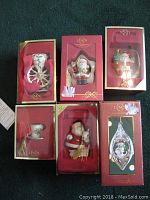 Six Lenox Christmas ornaments in original red boxes, displayed in a 2x3 arrangement showing the various Christmas figurines and decorations inside.