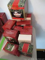 Photo showing all 12 Hallmark Keepsake Ornament original boxes stacked together, displaying variety of red and green box designs brandishing hallmark logo and ornament images.