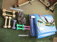Overview of all items showing hand weights, ankle weights, yoga mats and resistance bands on floor