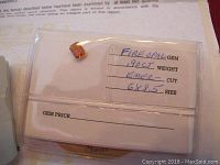 Single fire opal gemstone in a small plastic bag with a label indicating weight, cut and size.