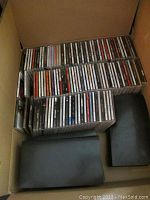 Box containing about 50 assorted music CDs in jewel cases.