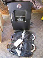 Photo of the black Smoky Mountain Series electric smoker with glass door and temperature gauge, along with a black carrying bag containing horseshoes.