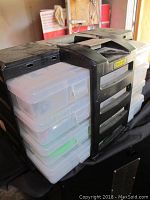 Black plastic multi-drawer fishing tackle organizer with transparent storage boxes inside.