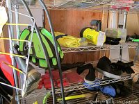 Scuba fins, goggles, snorkels, and related gear on metal shelving rack