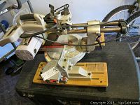 Sliding compound miter saw mounted on wooden platform, showing saw motor and blade arm.