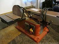 Overall view of Skil 3376 belt sander showing the sanding belt, disc, base, and power cord.