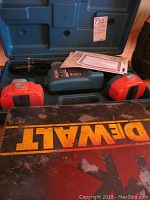 Photo showing two orange batteries and blue charger inside blue Makita drill case, a worn black and yellow DeWalt case below.