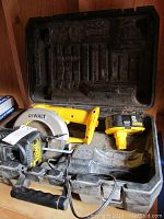DeWalt cordless circular saw, battery, and charger inside black carrying case showing overall condition and storage.