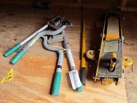 Photo showing two stud punches with green handles and a yellow hydraulic trolley jack with handle and wheels.