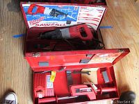 Open red Milwaukee metal case showing heavy-duty Sawzall and a red charger/18V battery pack