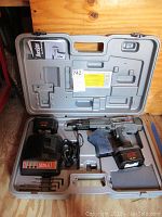 Open molded gray plastic carrying case containing a Senco DuraSpin DS202-14V screw fastening gun, two rechargeable batteries, battery charger, and small Allen wrenches.