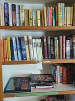 Full view of three shelves filled with fiction and mystery books
