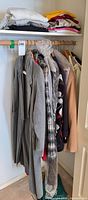 Closet rod with multiple coats and shelf of folded sweaters