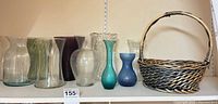 Front view of all nine vases lined on shelf with wicker basket