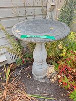 Full view of concrete birdbath beside siding