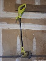 Full view of Ryobi P20103 string trimmer hanging on wall