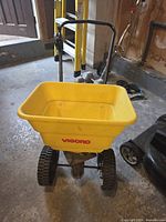 Full view of yellow Vigoro broadcast spreader showing hopper, handle and wheels