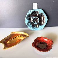 Group shot of three ceramic ashtrays in varied colors and shapes