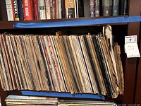 Full shelf view of vinyl records tightly packed, showing quantity and general sleeve wear