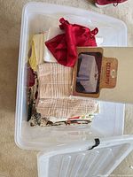 Tote with assorted folded linens, red piece, beige stripe cloths, Celebrity packaging visible