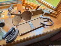 Overview of entire lot on windowsill: plane, spoons, slicer board, sad iron, horseshoe