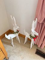 pair of white wooden reindeer holiday figures with wreath collars and bows