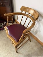Angled view of entire chair showing spindle back, armrest, vinyl seat