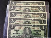 Fronts of five consecutive $1 bills in sleeves
